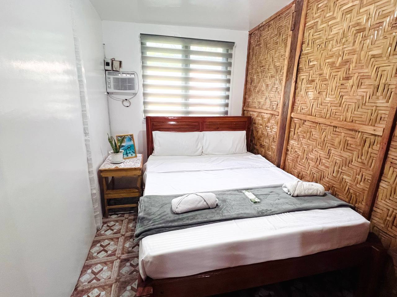 A bedroom in the Bamboo Villa with a timber headboard against a woven wall