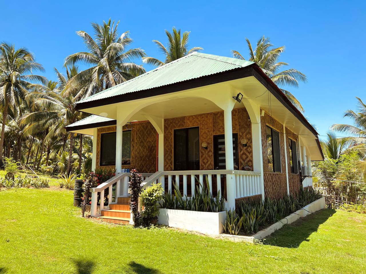 The Bungalow Villa with woven walls and a white veranda, standing on the lawn