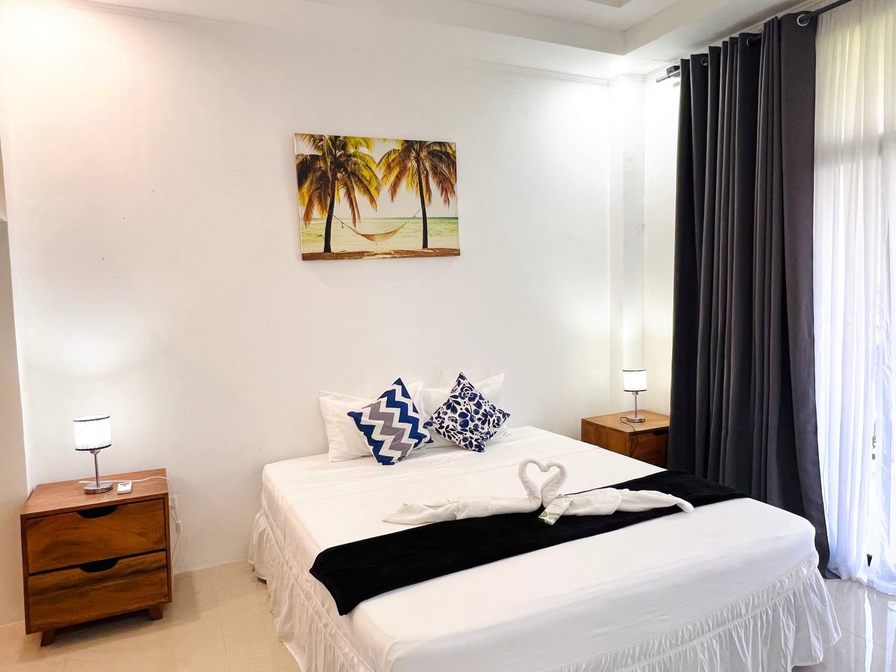 Bedroom in the Grande Suite with white linen and a floor lamp beside the bed
